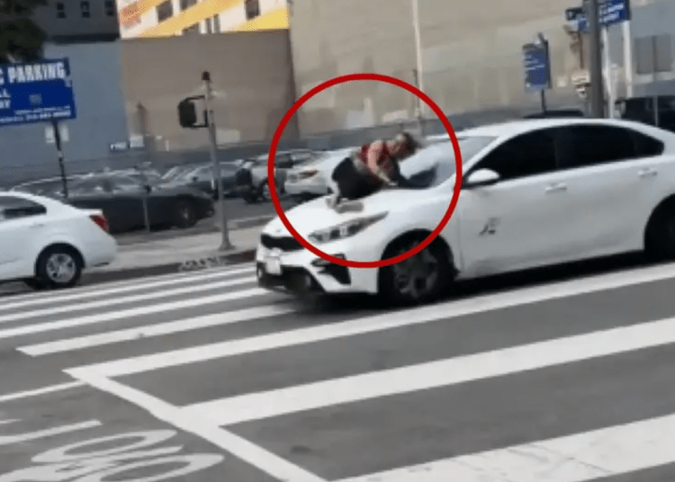 woman frantically holds onto hood